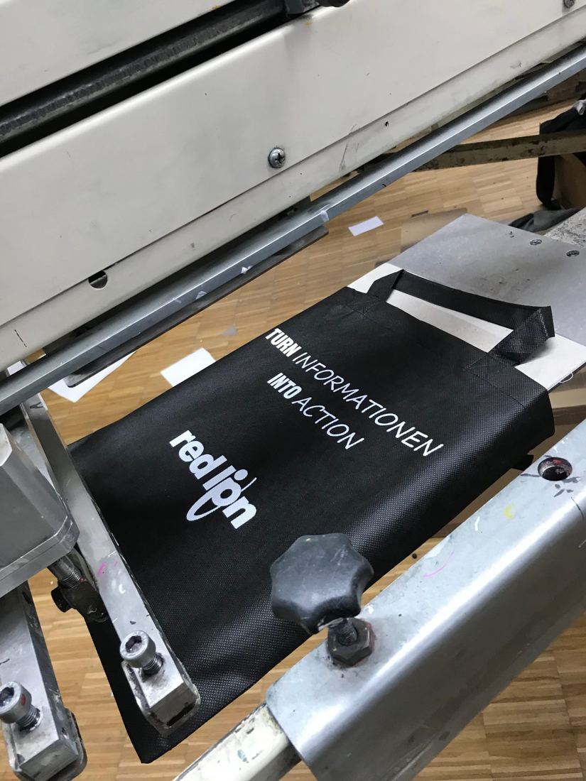Siebdruckmaschine beim Bedrucken eines schwarzen Shirts